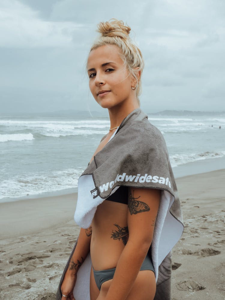 Woman In Gray Bathing Suit And Towel On Beach Shore