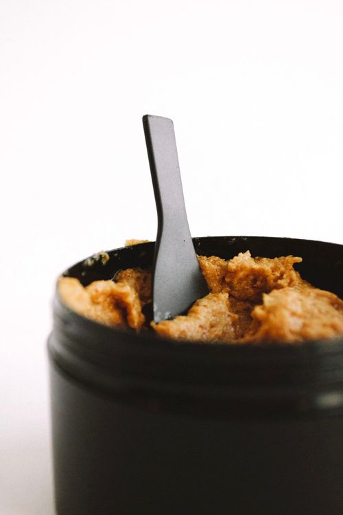 Free Close-up of a beauty product jar with dark exfoliating scrub and spatula. Stock Photo