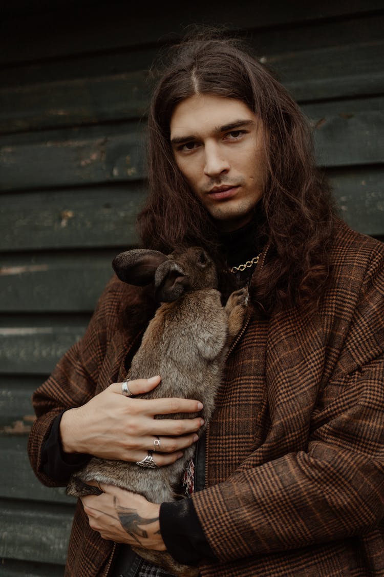 A Man Carrying A Brown Rabbit