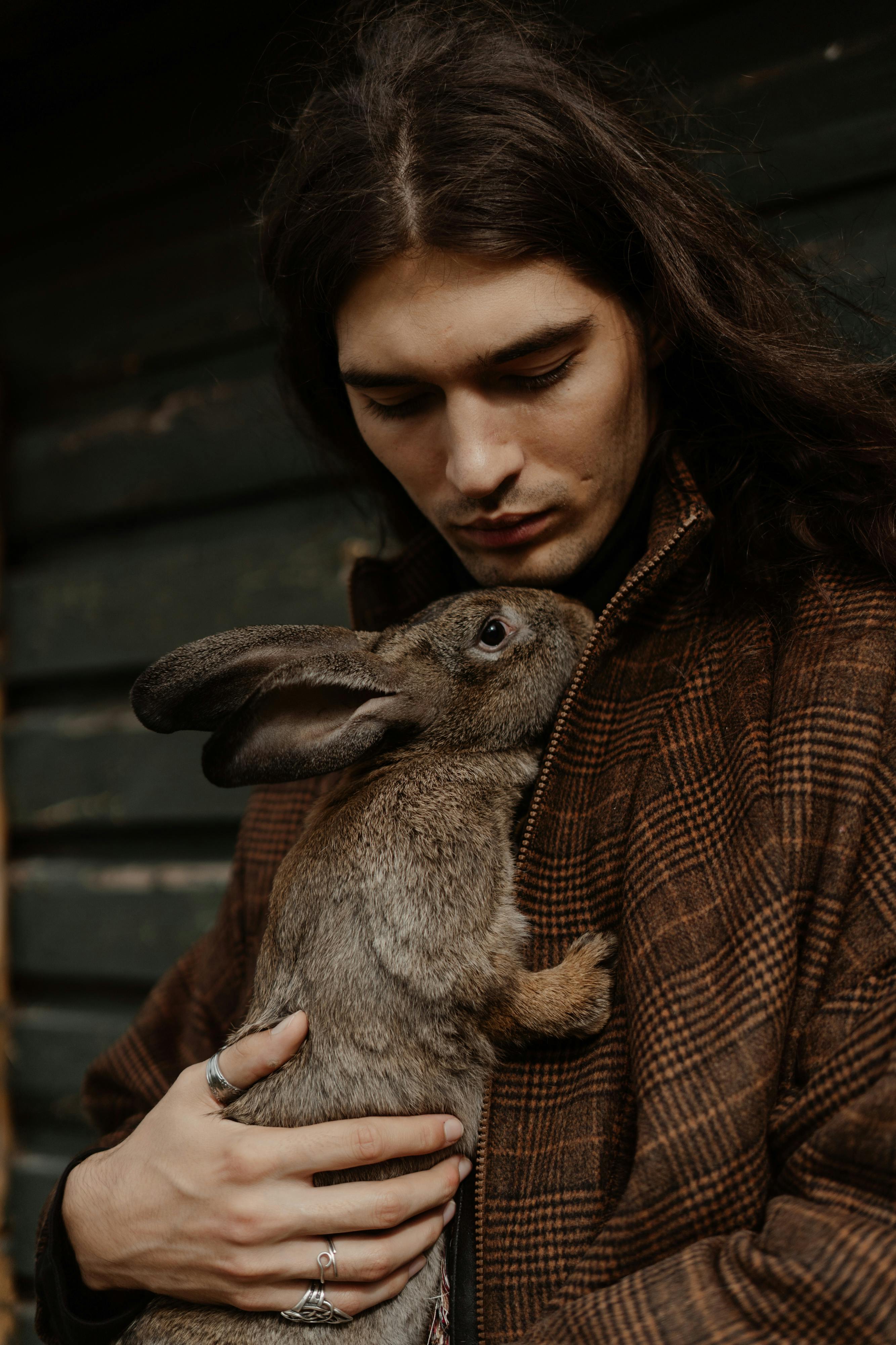 a man in brown coat holding a brown rabbit