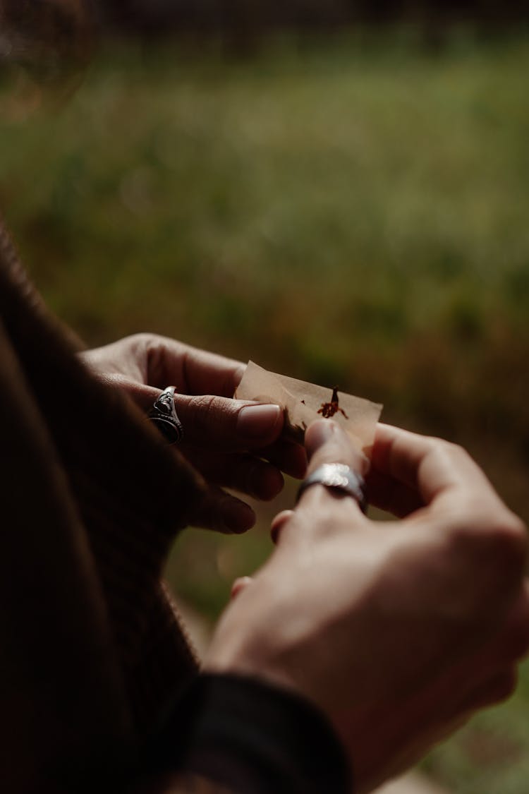 A Close-Up Shot Of A Person Rolling A Cigarette