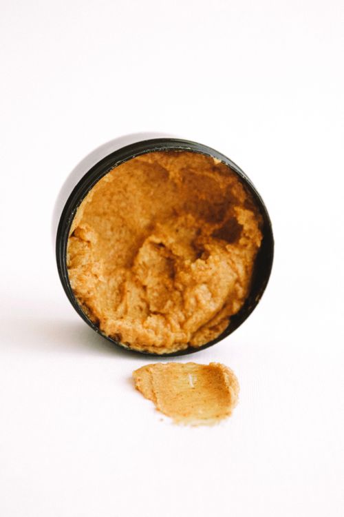 Free Open jar of natural body scrub with some spilled scrub against a white background. Stock Photo