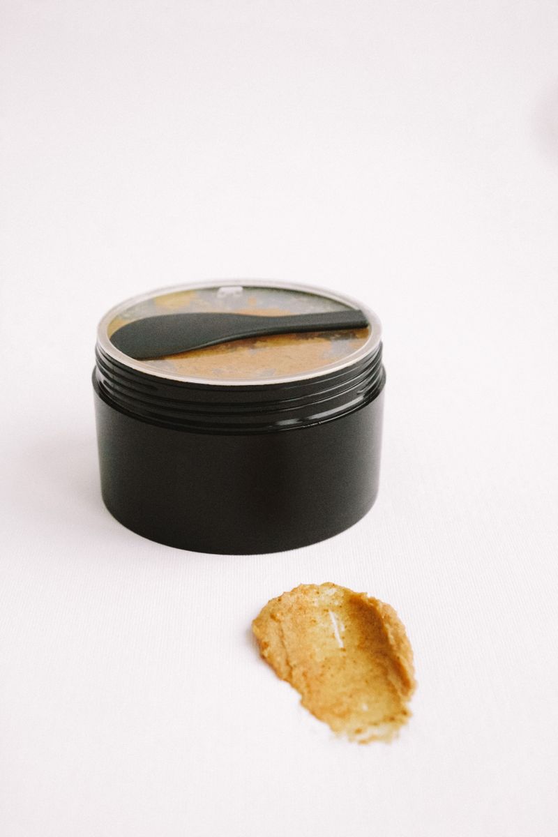 Black cosmetic jar with spread botanical scrub