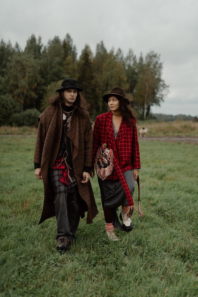 Man And Woman Walking On Grass Field