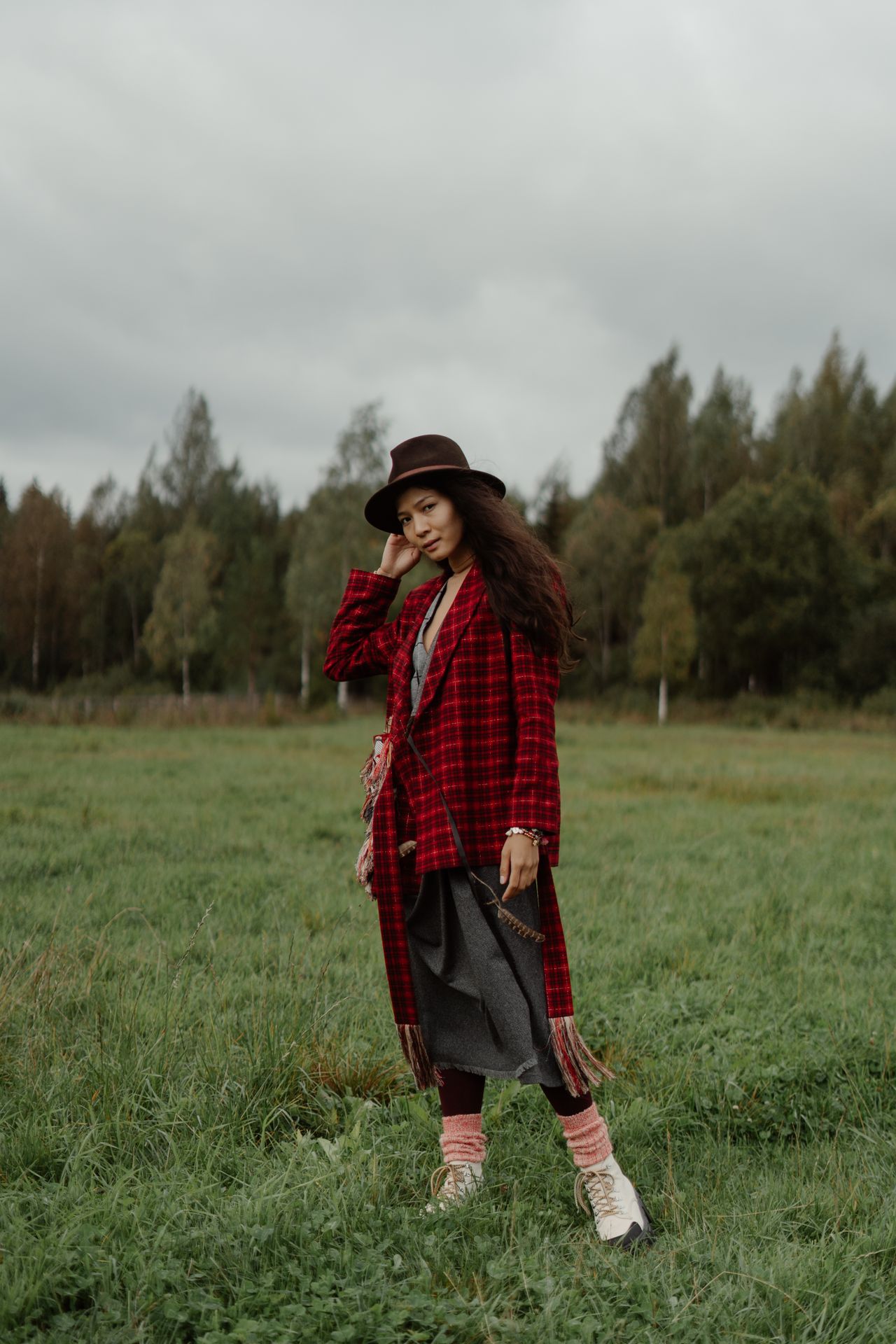 Woman in a red plaid coat and hat standing in an autumn field