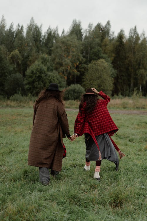 Free A Couple in a Plaid Coat Walking on a Field while Holding Hands  Stock Photo