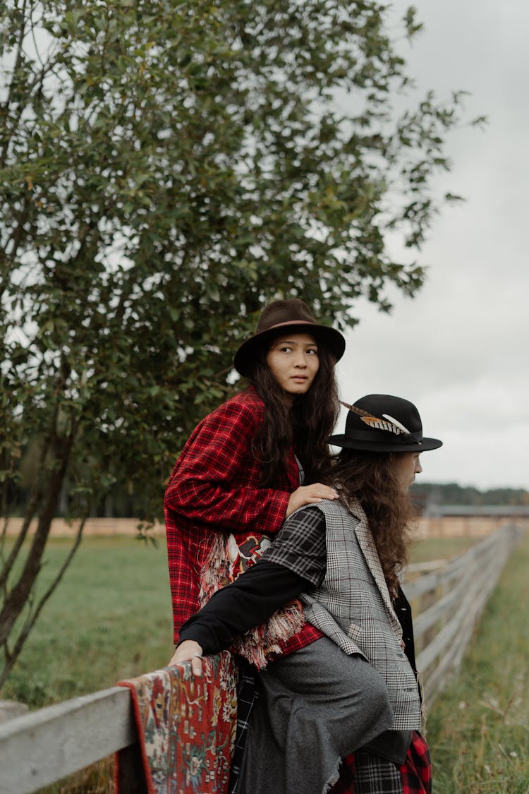 Woman Sitting On Fence Over Man Leaning On Fence