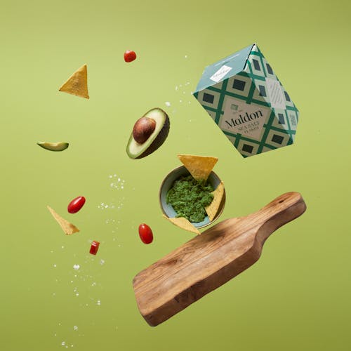 Brown Wooden Chopping Board and Avocado on Green Background