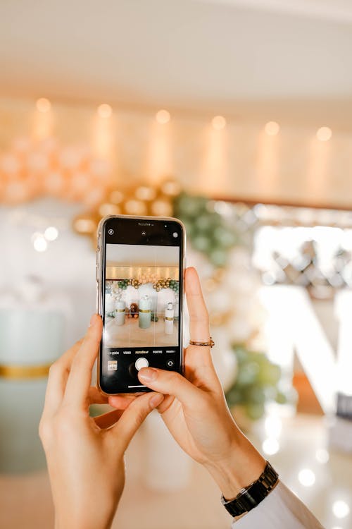 Hand Holding Smart Phone Photographing Interior Decorated with Balloons