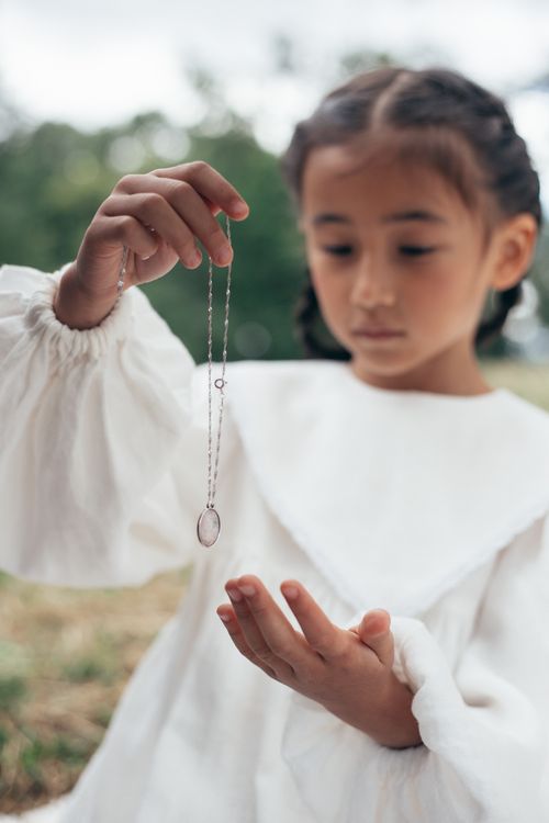 Free Portrait of a young girl with braided hair examining a necklace outdoors. Stock Photo