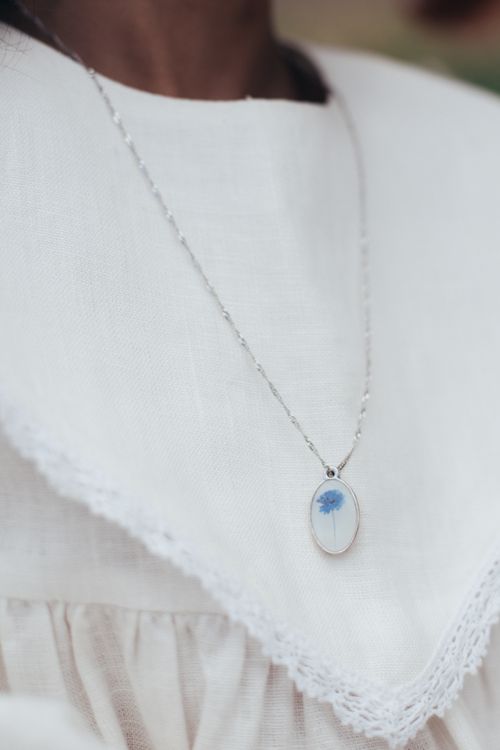 Free Close-up of a delicate pendant necklace on an elegant white dress, capturing elegance and simplicity. Stock Photo