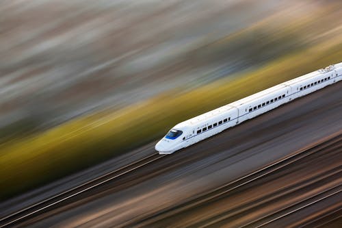 Free A sleek white high-speed train traveling at top speed, captured with a motion blur effect. Stock Photo