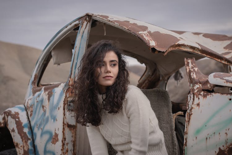 Woman In White Sweater Sitting On Wrecked Car