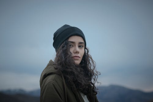 Photos gratuites de bonnet, cheveux bouclés, ciel sombre