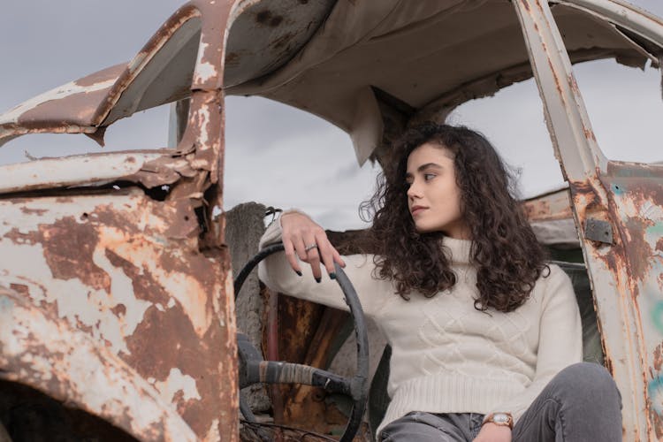 A Woman Sitting In A Broken Car