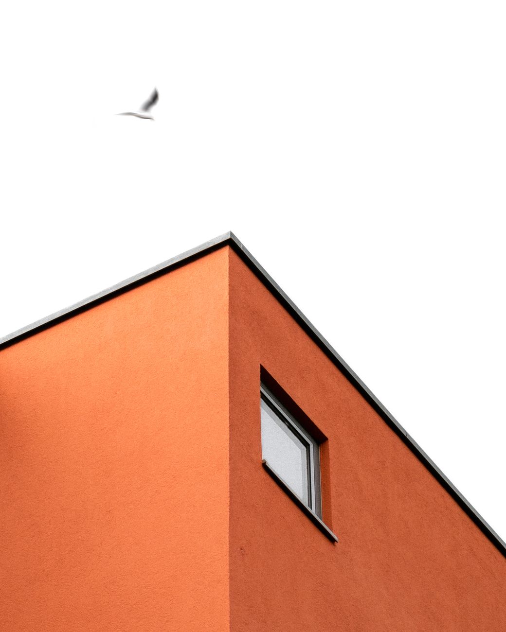 Low angle shot of modern orange building in Augsburg, showcasing minimalist architecture against a clear sky.