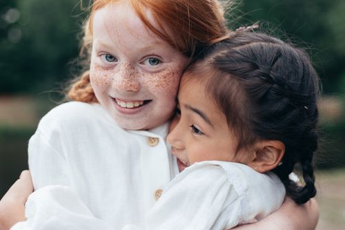 Free Two smiling girls embracing joyfully outdoors, symbolizing friendship and happiness. Stock Photo