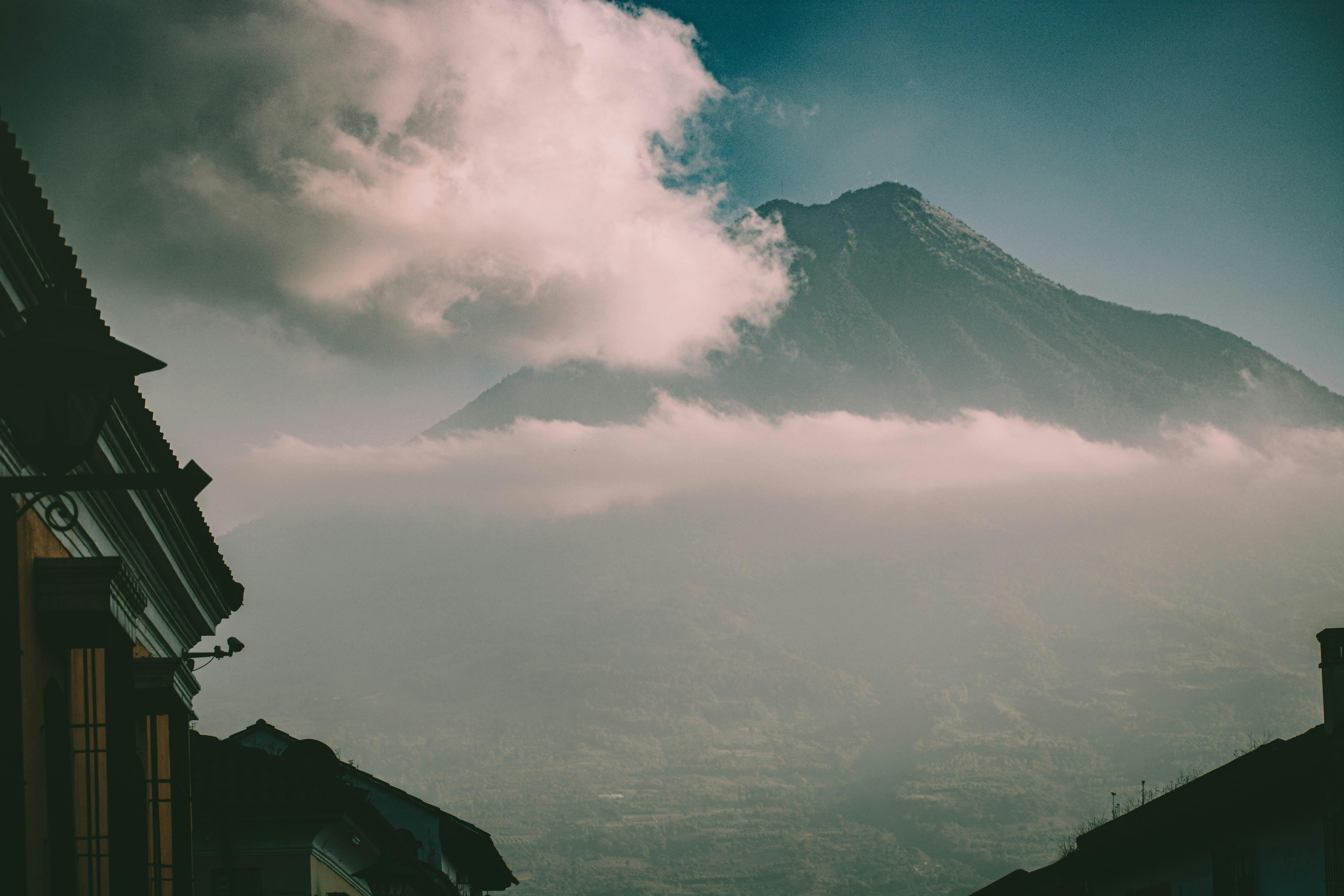 Dramatic view of a volcano with clouds over Ciudad de Guatemala's architecture. - Semuc Champey