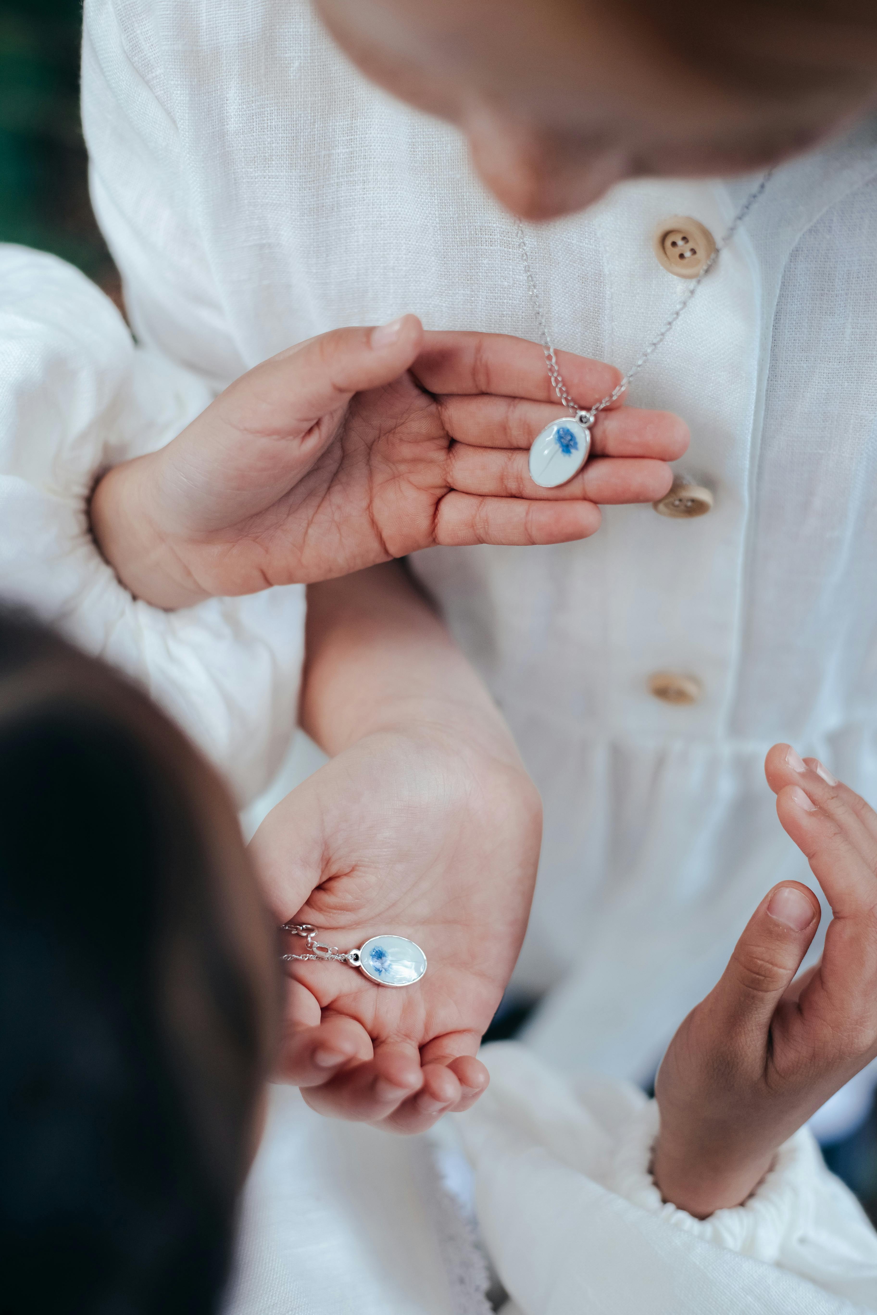 Close-up of children sharing silver necklaces with blue pendants.