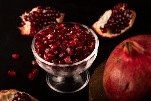 Close-up of fresh pomegranate seeds in a clear glass bowl, highlighting their vibrant red color.