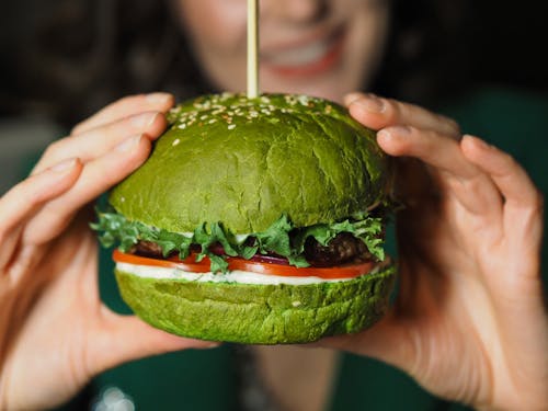 A Woman Holding a Burger with Green Buns