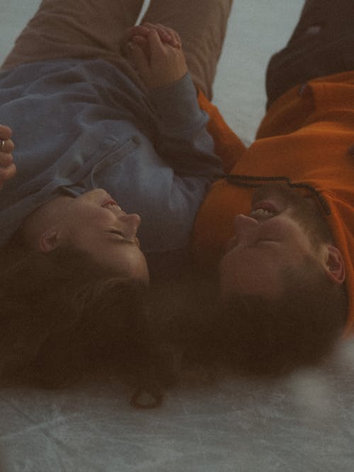 Free Smiling Couple Lying on Floor and Holding Hands Stock Photo