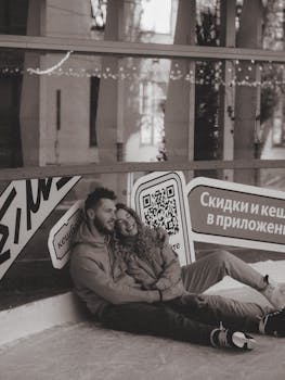 A happy couple in a cozy embrace on an ice rink, captured in monochrome, expressing joy and togetherness.