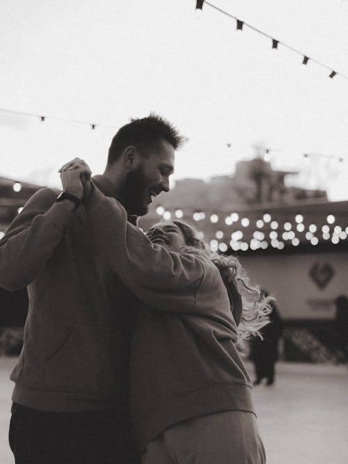 Free Smiling Couple Dancing Outdoors, Black and White Stock Photo