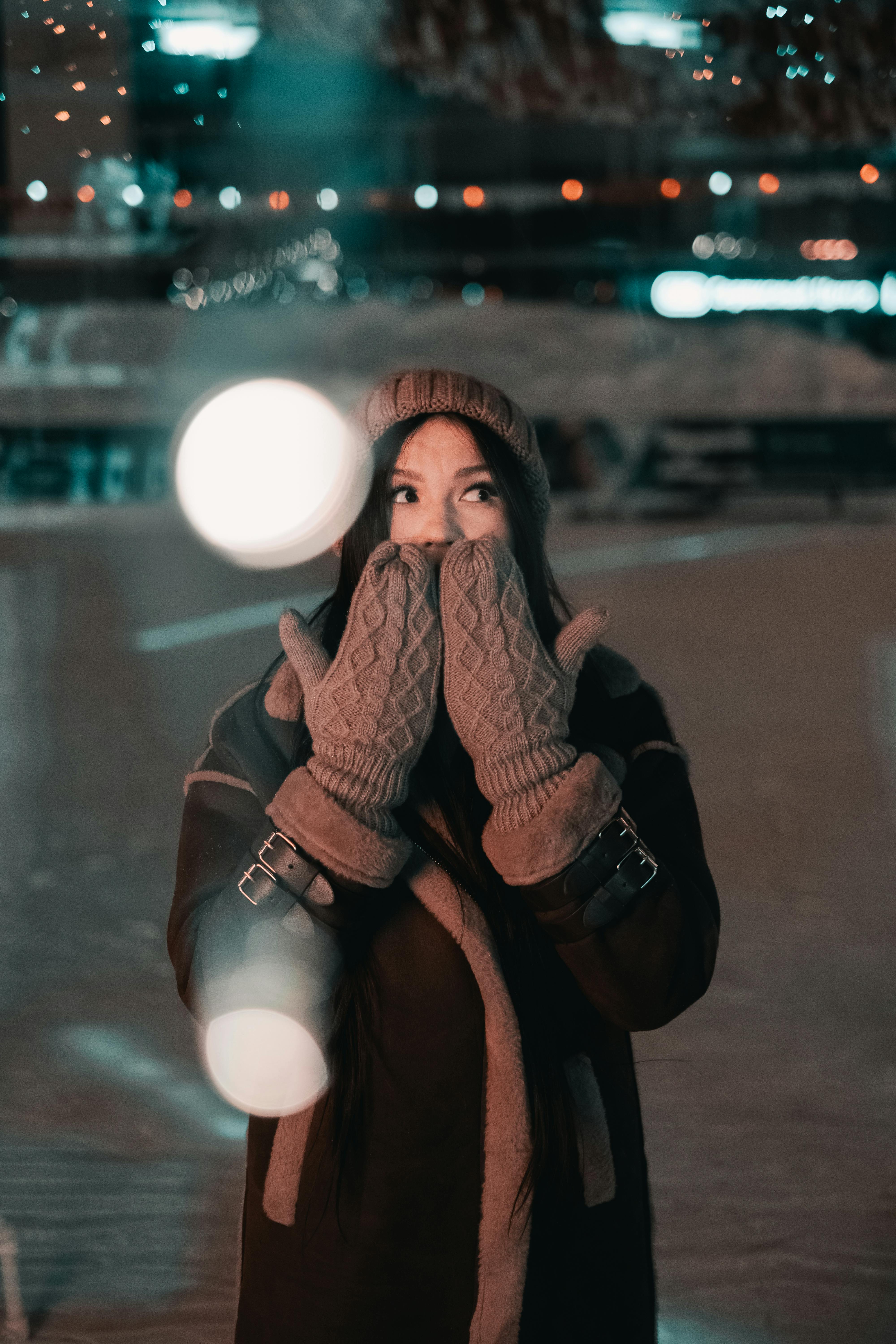 A woman in cozy winter attire outdoors at night, creating a warm, festive mood.