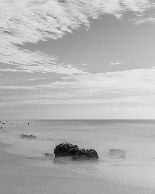 Free A serene black and white image of a coastal beach in Brazil with calm waters and fluffy clouds. Stock Photo