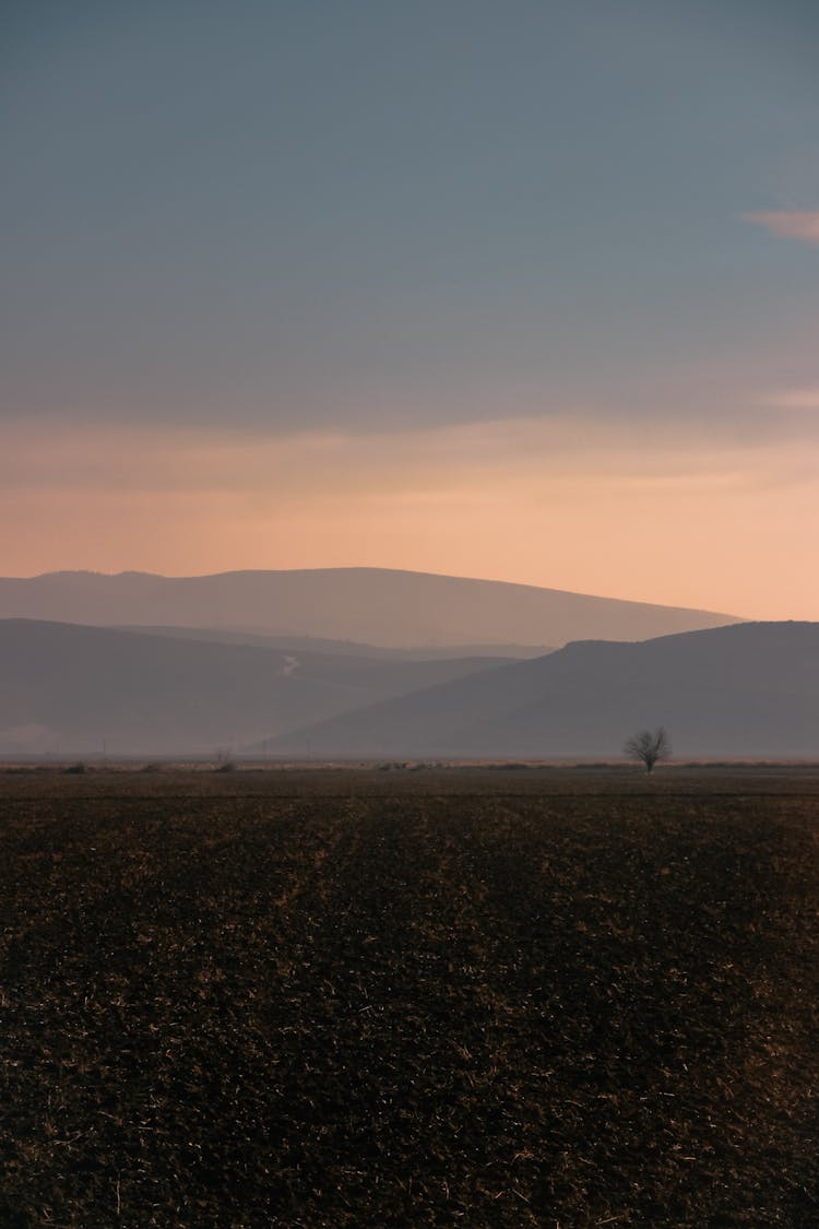 Clouds Over Hills And Field At Dusk