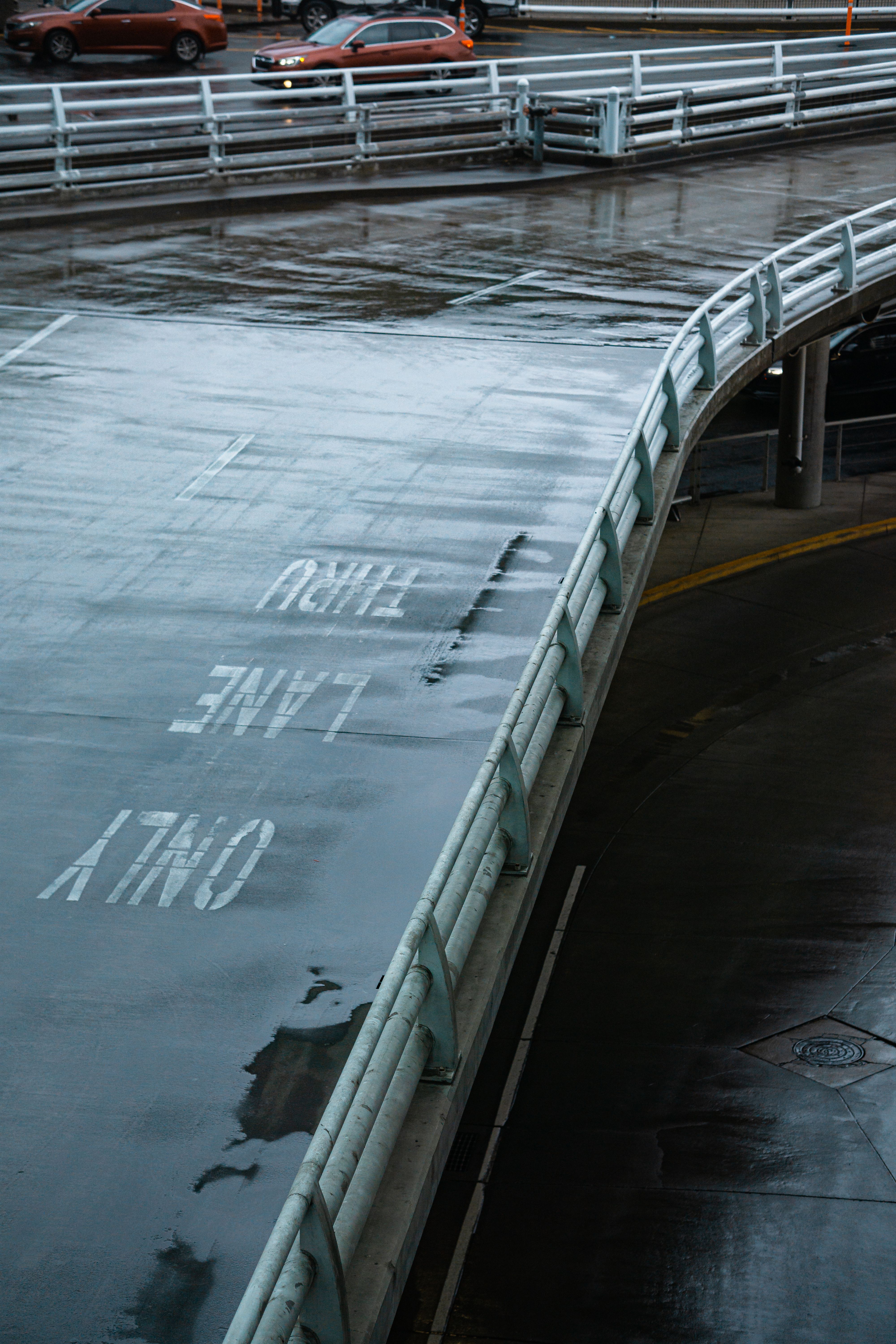An aerial view of a wet urban road with visible lane markings and cars driving.