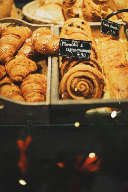 Close-up of various fresh pastries including croissants and cinnamon rolls on display in a Warsaw bakery.