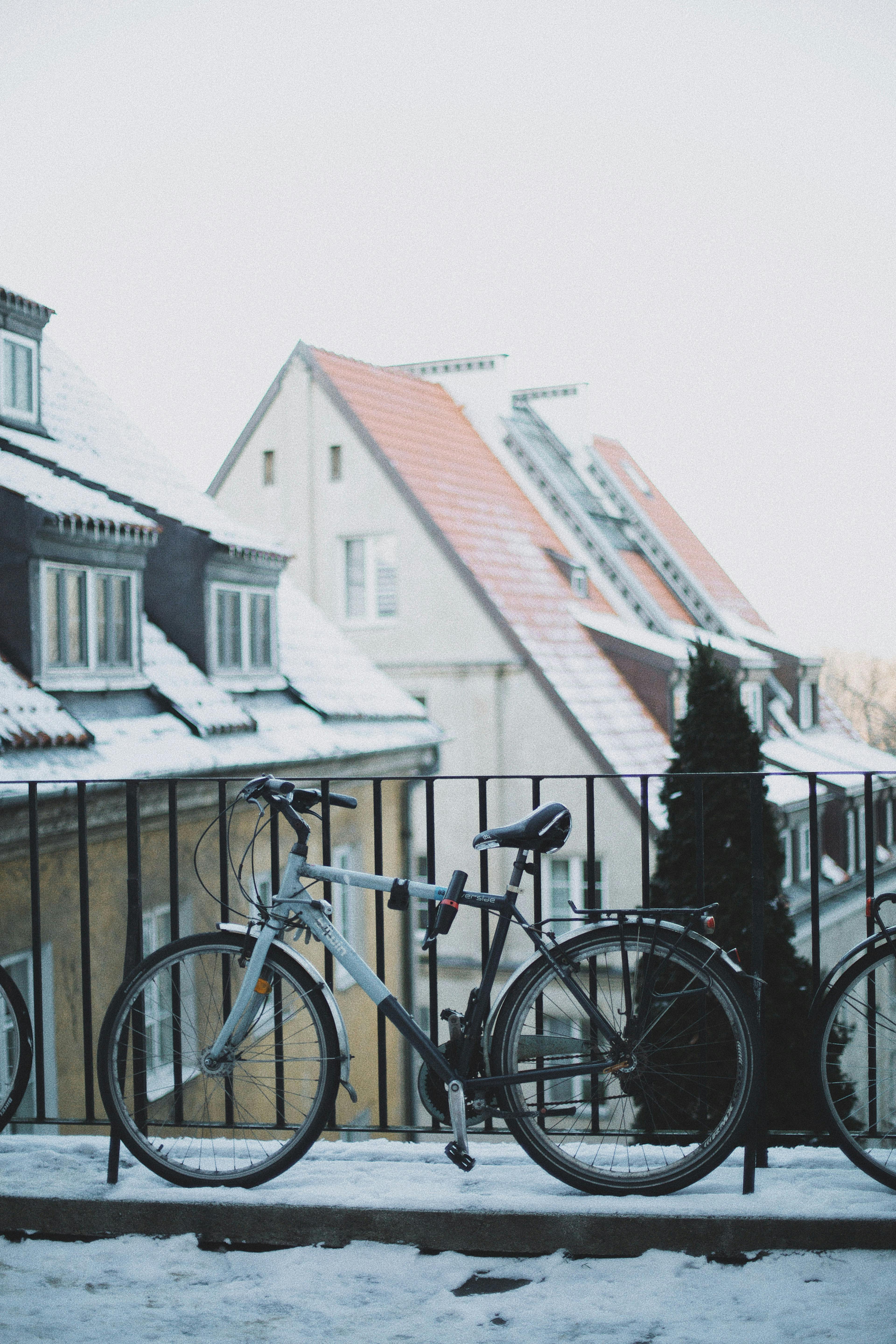 A serene winter scene of a snow-covered street in Warsaw featuring a parked bicycle against traditional architecture.