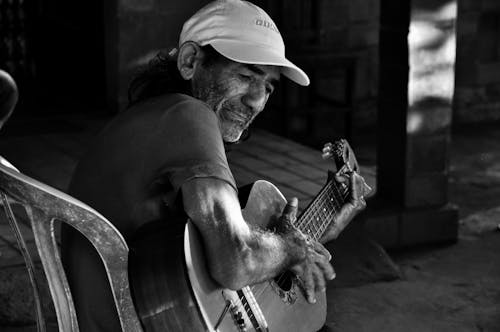 Man Sitting on Chair Playing Acoustic Guitar