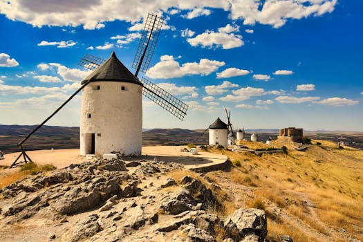 Scenic view of traditional windmills in Consuegra, Spain with a bright blue sky.