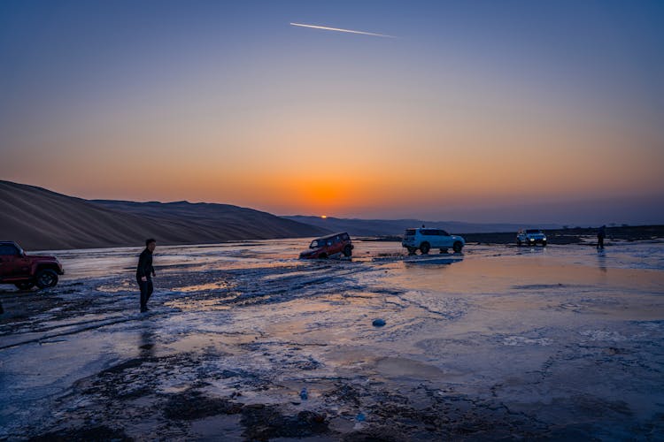 Cars On Frozen Lake At Sunset