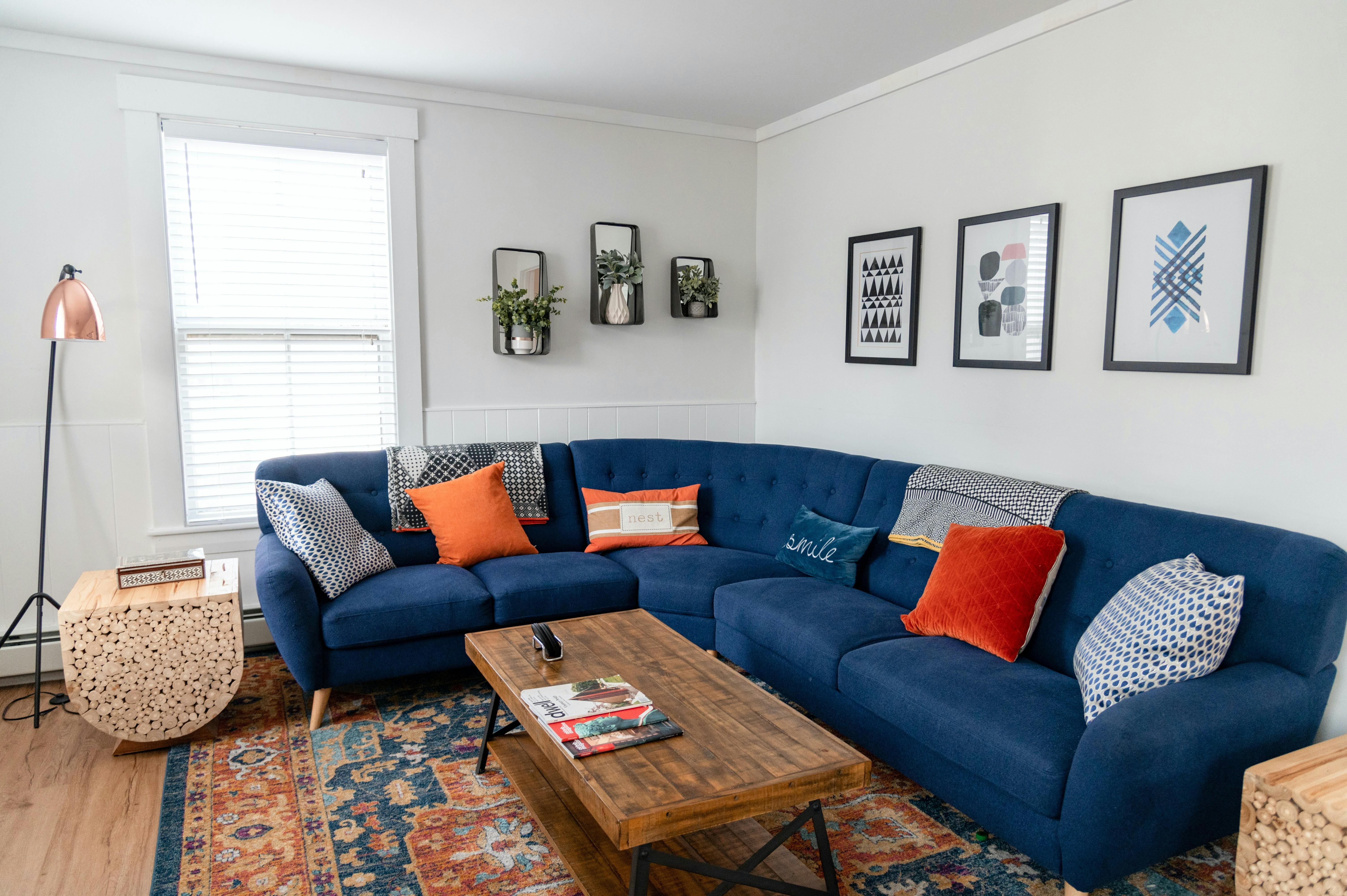 Free Bright and stylish living room featuring a blue sectional, vibrant pillows, and modern decor. Stock Photo
