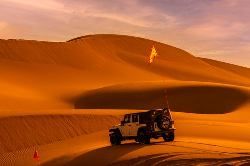 Free A thrilling SUV adventure in stunning desert sand dunes under the warm sunset light. Stock Photo