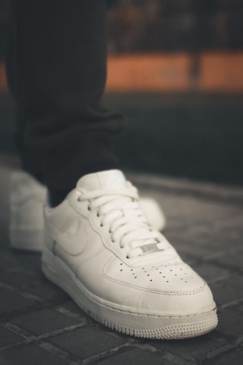 Free Close-up of a modern white sneaker on a city pavement, showcasing fashion-forward footwear. Stock Photo