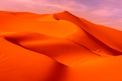 Free Stunning sand dunes glow under a warm desert sky, showcasing nature's beauty. Stock Photo