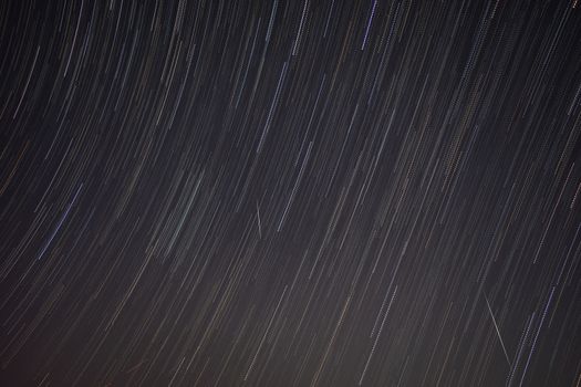 Captivating long exposure shot of star trails creating a dynamic pattern in the night sky.