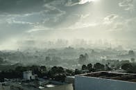 巴西利亚的城市景观笼罩在雾气中，多云的天空下，建筑物和树木若隐若现