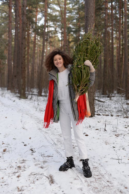 Woman in Checkered Jacket Carrying a Christmas Tree