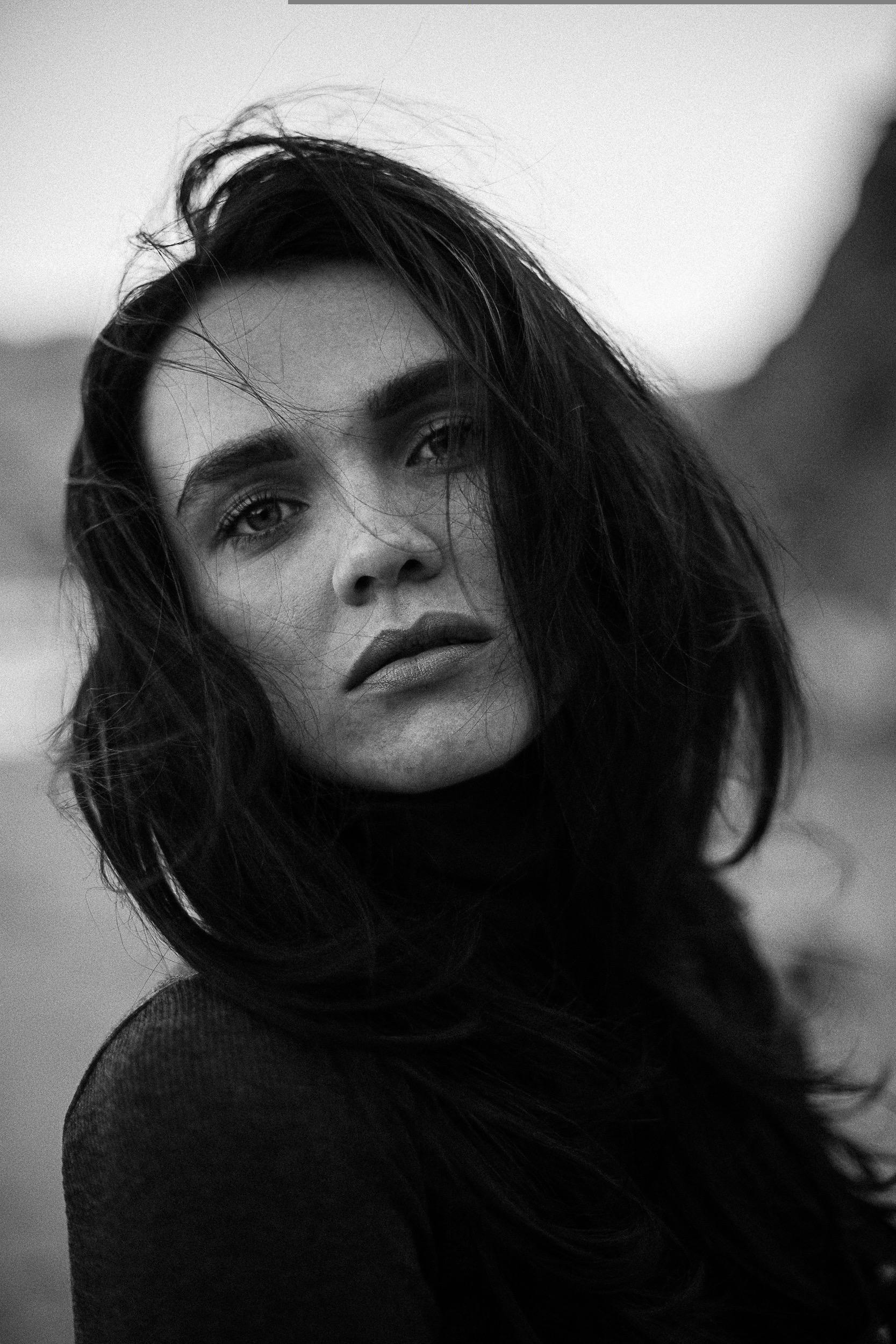 Stunning black and white portrait of a woman with messy hair and intense gaze.