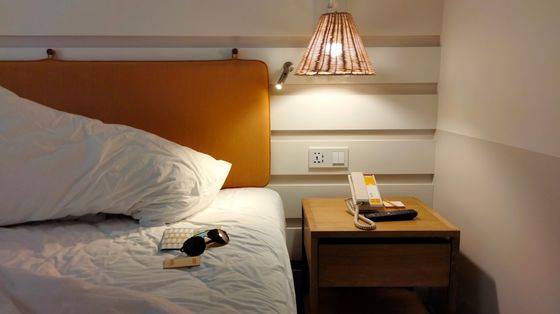 Bedside lamp and nightstand in a hotel room — photo by Natthanon Chinnasri on Pexels