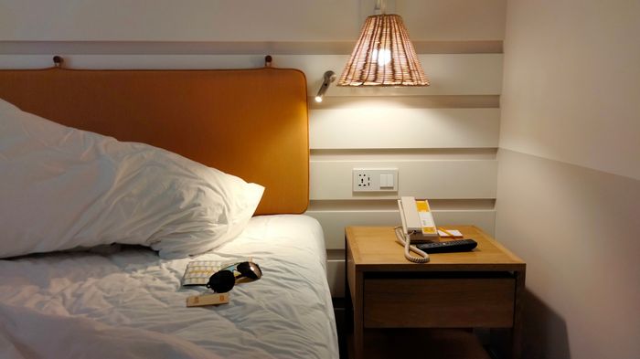 Made-up guest bed and nightstand, photo by Natthanon Chinnasri on Pexels