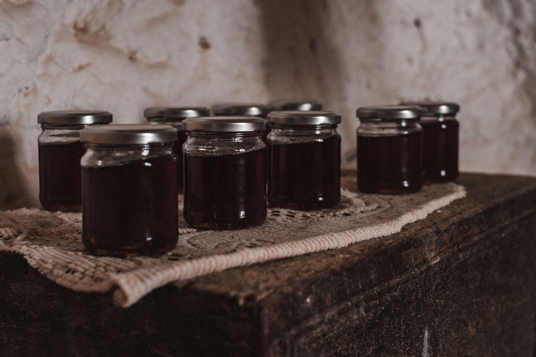 Potes de compota caseira de figo alinhados numa mesa rústica de cozinha sob luz quente de outono