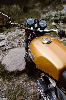 A shiny golden Ducati motorcycle parked on rocky terrain, offering a close-up of its controls and design.