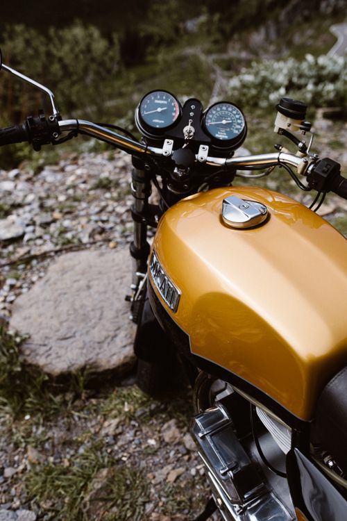 Free A shiny golden Ducati motorcycle parked on rocky terrain, offering a close-up of its controls and design. Stock Photo